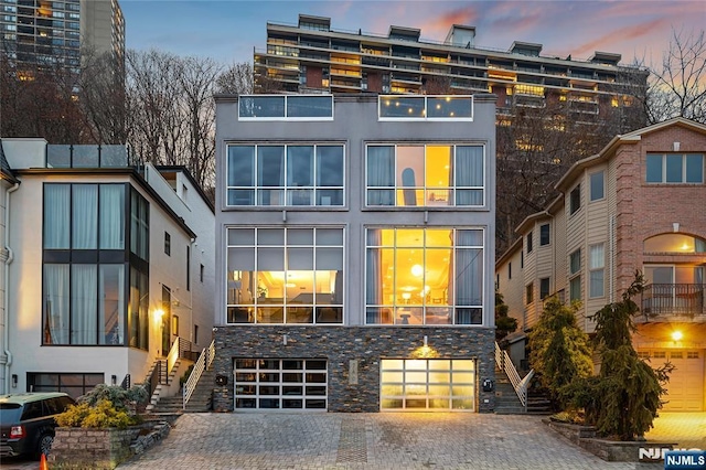 view of front of property featuring stucco siding, stairs, decorative driveway, and a garage