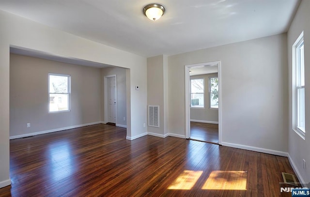 empty room with visible vents, plenty of natural light, and wood finished floors