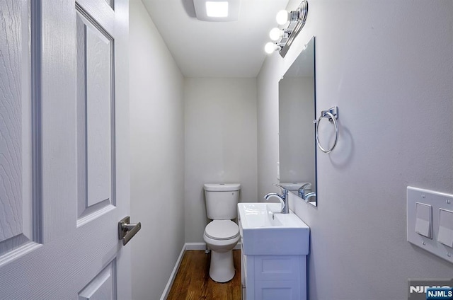 bathroom with baseboards, toilet, wood finished floors, and vanity