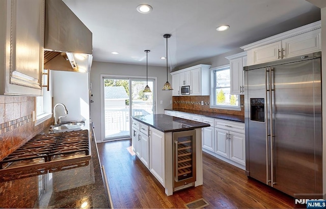 kitchen featuring extractor fan, beverage cooler, white cabinets, stainless steel appliances, and a sink