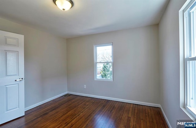 empty room with baseboards and dark wood-type flooring