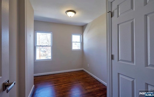 empty room with dark wood-style floors and baseboards