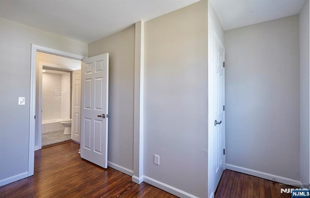 unfurnished bedroom featuring baseboards and dark wood-style flooring