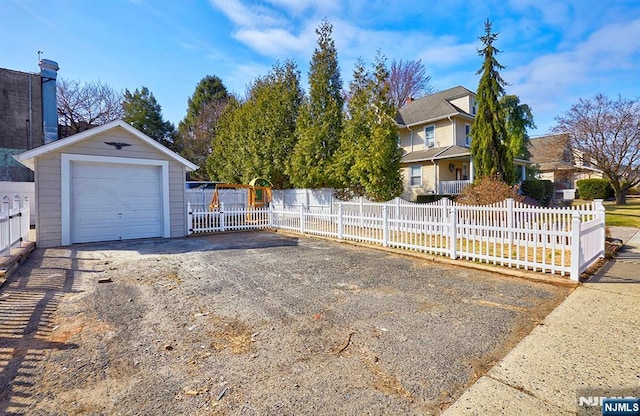 exterior space with a fenced front yard, an outbuilding, and driveway