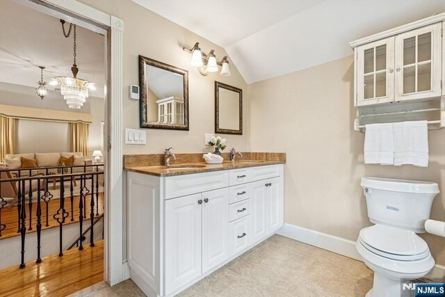 274 Ridgewood, Glen Ridge, NJ 07028 - full bath with double vanity, baseboards, vaulted ceiling, toilet, and a chandelier