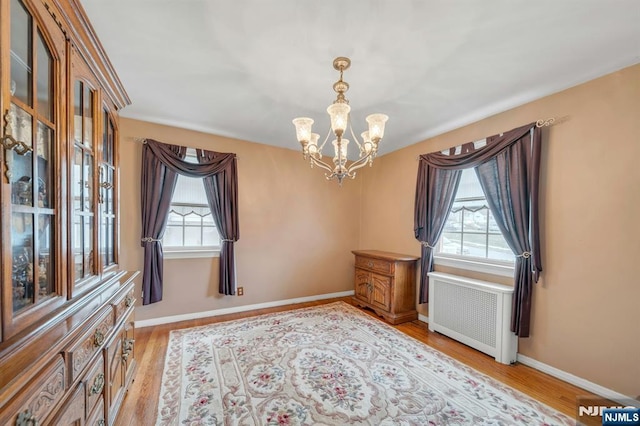 interior space featuring light wood-type flooring, plenty of natural light, a chandelier, and radiator heating unit
