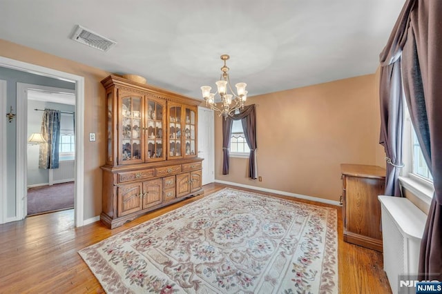 dining room with a chandelier, visible vents, light wood-style flooring, and baseboards