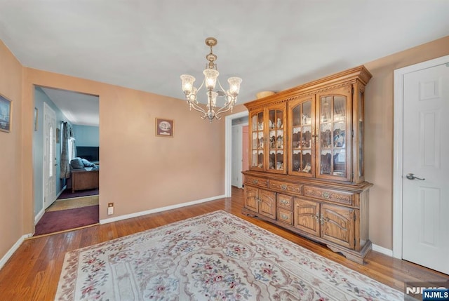 dining space with baseboards, an inviting chandelier, and wood finished floors
