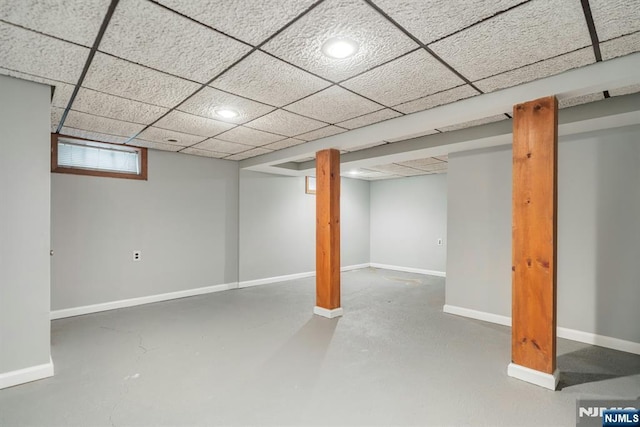 below grade area featuring a paneled ceiling and baseboards