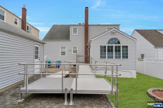 rear view of property with a lawn, a deck, and fence