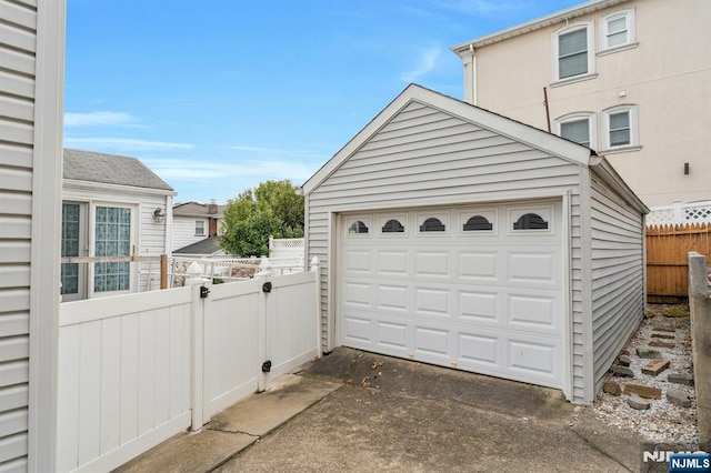 detached garage with concrete driveway and fence