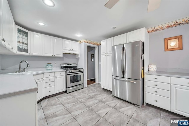 kitchen with a sink, light countertops, under cabinet range hood, appliances with stainless steel finishes, and white cabinetry