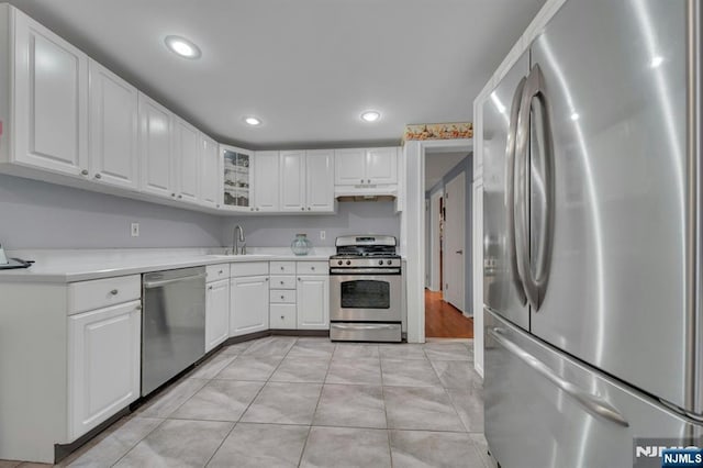 kitchen with under cabinet range hood, white cabinetry, appliances with stainless steel finishes, and a sink