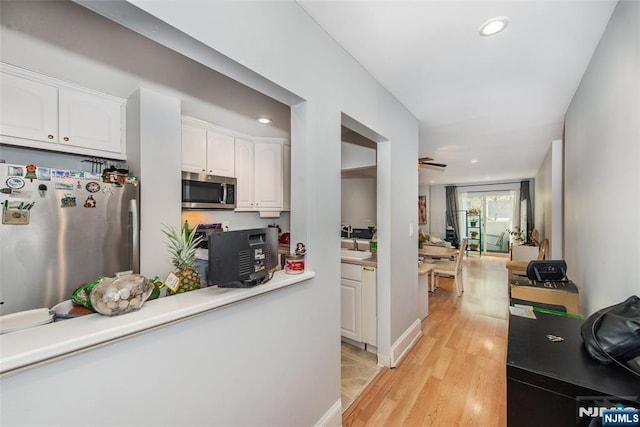 kitchen featuring light wood finished floors, recessed lighting, stainless steel appliances, white cabinetry, and a sink