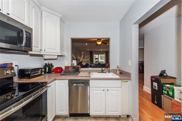 kitchen featuring a ceiling fan, a toaster, a sink, white cabinets, and appliances with stainless steel finishes