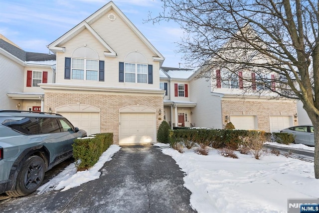 view of front of house featuring brick siding, driveway, and a garage