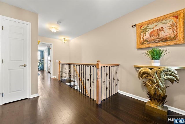 hall featuring an upstairs landing, baseboards, and hardwood / wood-style floors