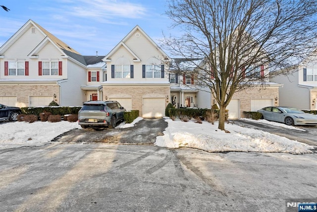 view of property featuring an attached garage, brick siding, and driveway