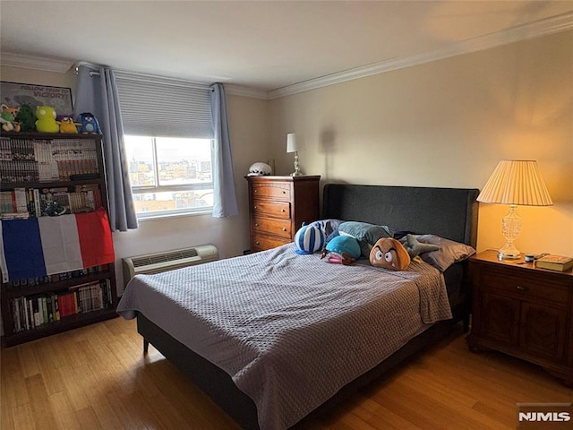 bedroom with an AC wall unit, wood finished floors, and ornamental molding