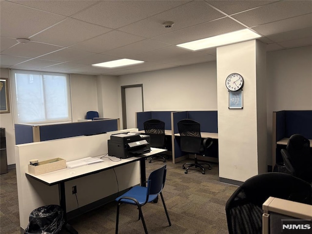 office space with dark carpet, a paneled ceiling, and baseboards