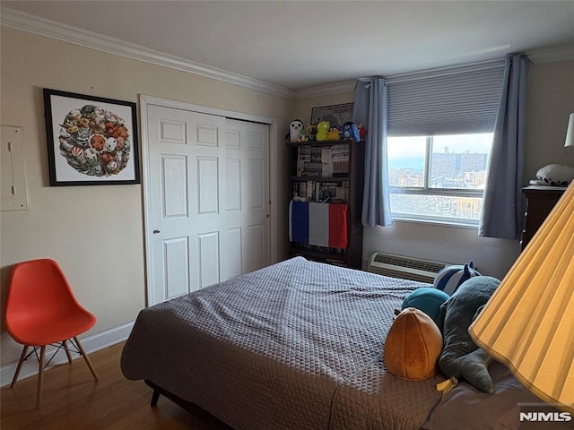 bedroom featuring baseboards, wood finished floors, a wall unit AC, and ornamental molding