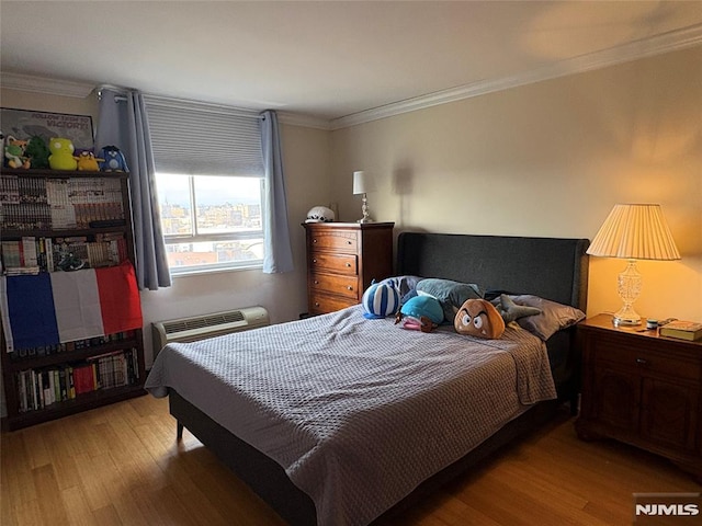 bedroom featuring an AC wall unit, wood finished floors, and ornamental molding