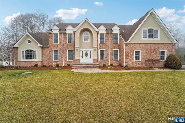 view of front of house featuring brick siding, stucco siding, and a front yard
