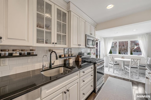 kitchen with a sink, decorative backsplash, stainless steel appliances, and dark wood-type flooring