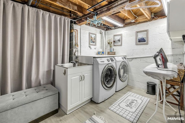 laundry room featuring washer and clothes dryer, a sink, light wood-style flooring, and concrete block wall
