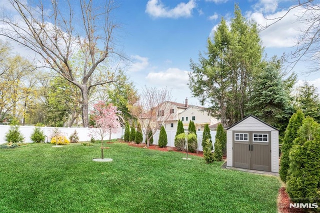view of yard featuring a shed, an outbuilding, and fence