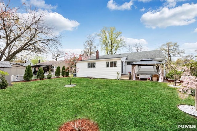 back of property featuring a gazebo, a yard, and a chimney