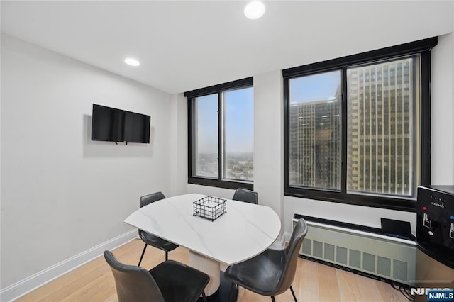 dining area with recessed lighting, radiator, wood finished floors, and baseboards