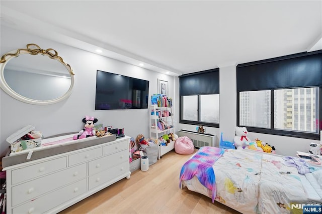 bedroom with recessed lighting, light wood-type flooring, and radiator