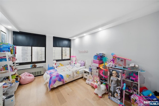 bedroom with recessed lighting, wood finished floors, and radiator heating unit