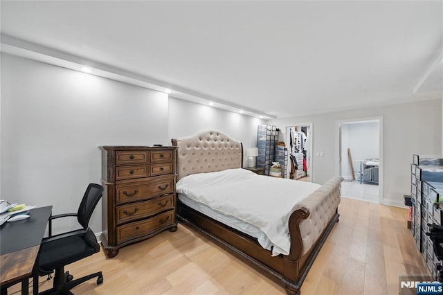 bedroom featuring connected bathroom, light wood-type flooring, and baseboards