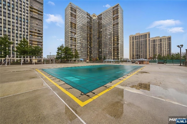 pool with fence, a city view, and a patio area
