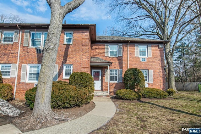 view of property with a front lawn, fence, and brick siding