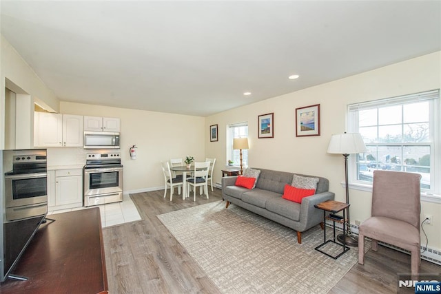 living room with light wood finished floors, recessed lighting, and baseboards