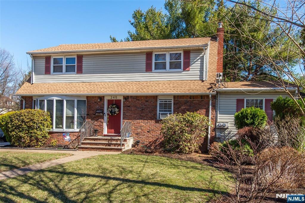 245 Grant Ave, Pompton Lakes, NJ 07442 - traditional-style home featuring brick siding, a chimney, and a front yard