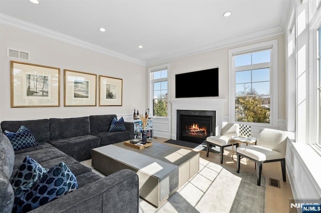 living room with a fireplace with flush hearth, visible vents, and ornamental molding