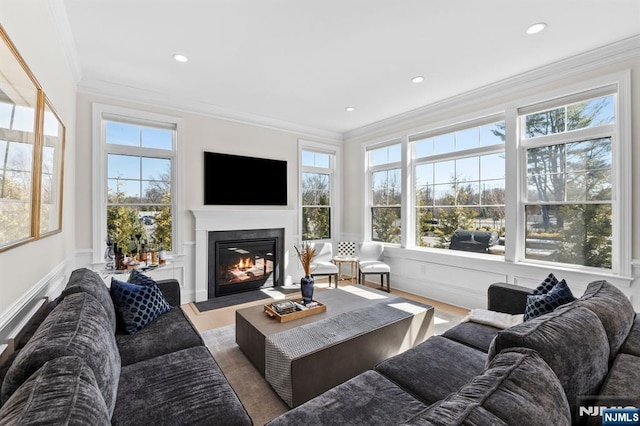 living area featuring wood finished floors, recessed lighting, a glass covered fireplace, and crown molding