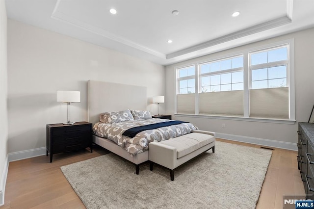 bedroom featuring a raised ceiling, baseboards, light wood-style flooring, and recessed lighting
