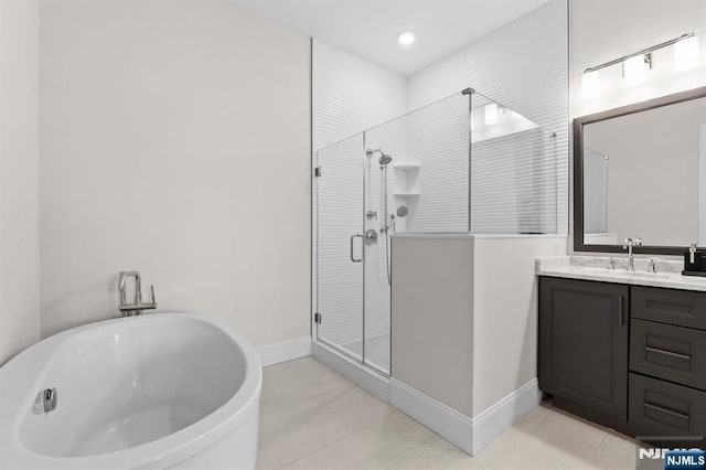 full bath featuring vanity, a shower stall, a soaking tub, tile patterned flooring, and baseboards