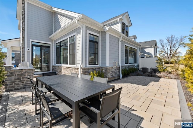 view of patio featuring an outdoor kitchen, outdoor dining area, central AC, and fence