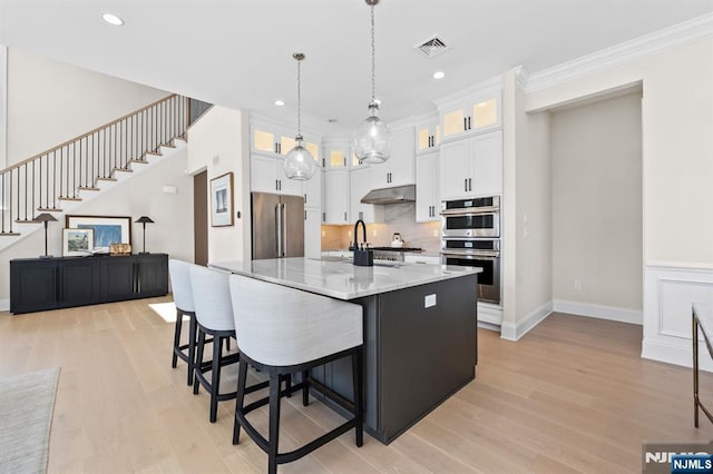 kitchen with visible vents, light wood-style floors, under cabinet range hood, and appliances with stainless steel finishes