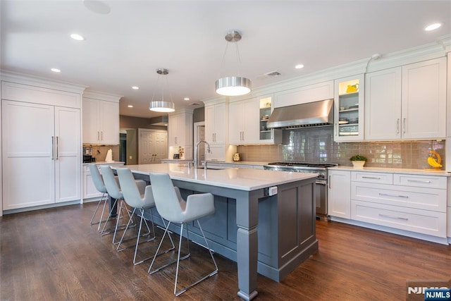 kitchen with wall chimney range hood, white cabinetry, and high end range