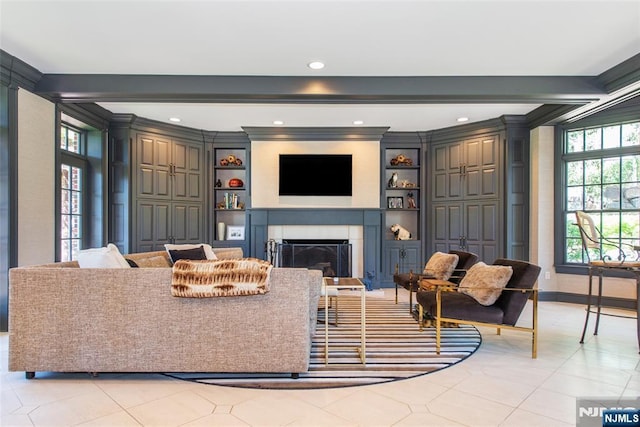 living room with built in features, a fireplace, light tile patterned floors, baseboards, and ornamental molding