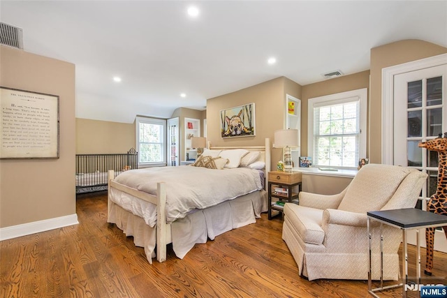 bedroom with visible vents, multiple windows, and wood finished floors