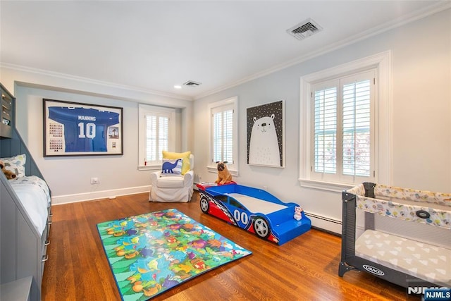 bedroom with crown molding, visible vents, and wood finished floors