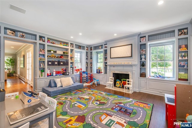 living area with crown molding, baseboard heating, a premium fireplace, recessed lighting, and wood finished floors